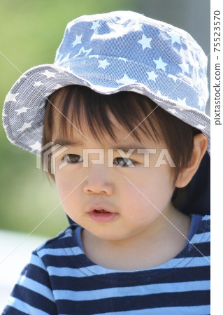 一個2歲男孩，戴著鬱金香帽子，在散步時停下來 75523570