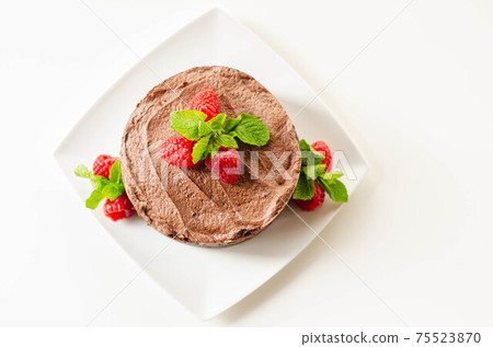 Gluten free tasty round cake based on Belgian chocolate decorated with fresh raspberries and mint Gluten free tasty round cake based on Belgian chocolate decorated with fresh raspberries and mint 75523870