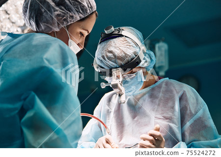 Rhinoplasty men, the surgeons gloved hands hold the instruments during nose surgery. Doctor in gloves holds a medical instrument during rhinoplasty 75524272