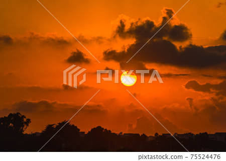Red and orange dramatic colorful clouds lit by evening sunset light Red and orange dramatic colorful clouds lit by evening sunset light 75524476