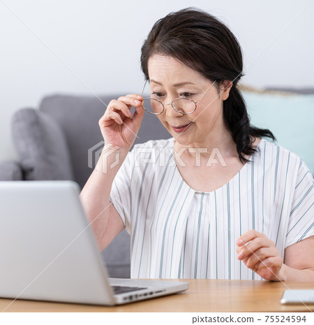 Presbyopia: A senior woman who wears reading glasses and looks at a computer without seeing the screen well. Square Presbyopia: A senior woman who wears reading glasses and looks at a computer without seeing the screen well. Square 75524594