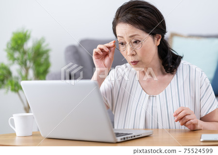 老花眼：一位老婦，戴著老花鏡，看電腦時看不到屏幕。 75524599