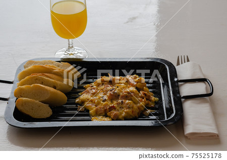Scrambled eggs served with orange juice and fresh baguette Scrambled eggs served with orange juice and fresh baguette 75525178