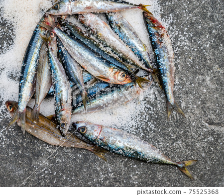 Whole raw organic mackerel fish with sea salt lying on a flat surface Whole raw organic mackerel fish with sea salt lying on a flat surface 75525368