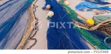 Industrial Fishing Equipment Fishnets and Fishing Lines lying on concrete in the port 75525409