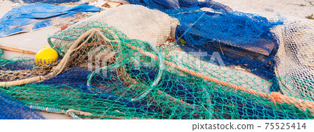 Industrial Fishing Equipment Fishnets and Fishing Lines lying on concrete in the port 75525414