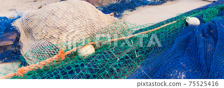 Industrial Fishing Equipment Fishnets and Fishing Lines lying on concrete in the port 75525416