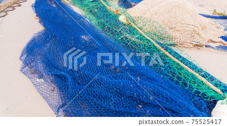 Industrial Fishing Equipment Fishnets and Fishing Lines lying on concrete in the port 75525417