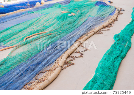 Industrial Fishing Equipment Fishnets and Fishing Lines lying on concrete in the port Industrial Fishing Equipment Fishnets and Fishing Lines lying on concrete in the port 75525449