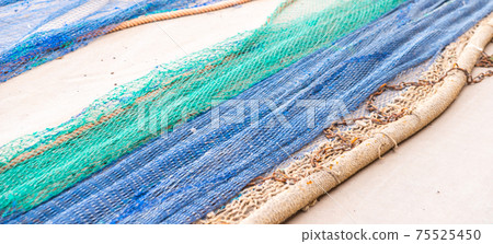 Industrial Fishing Equipment Fishnets and Fishing Lines lying on concrete in the port Industrial Fishing Equipment Fishnets and Fishing Lines lying on concrete in the port 75525450