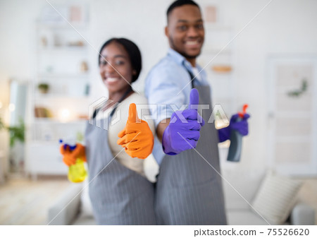 House cleaning concept. Happy black couple in rubber gloves showing thumbs up gesture at home, selective focus 75526620