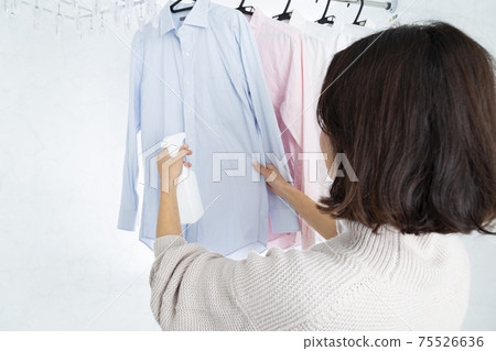 Woman spraying laundry Woman spraying laundry 75526636