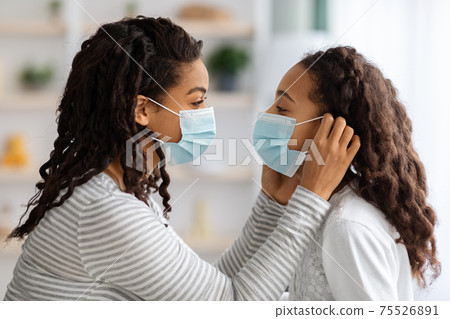 Side view of woman putting face mask on her daughter 75526891