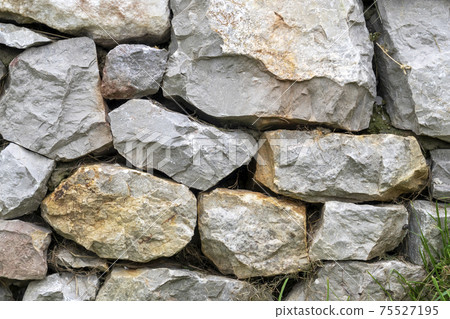 Stone wall with stacked natural stones close-up. Natural rock background Stone wall with stacked natural stones close-up. Natural rock background 75527195