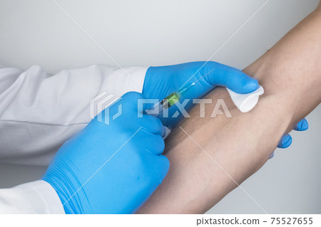 A doctor in blue medical gloves makes an injection into a vein. Intravenous drug administration. The concept of providing professional medical care 75527655