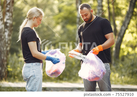 Couple collects garbage in garbage bags in park 75527910