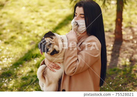 Brunette in a mask walks with pug Brunette in a mask walks with pug 75528021