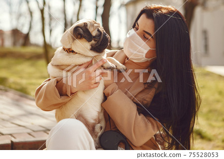 Brunette in a mask walks with pug 75528053