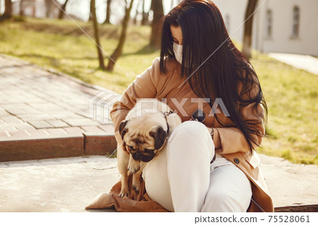 Brunette in a mask walks with pug Brunette in a mask walks with pug 75528061