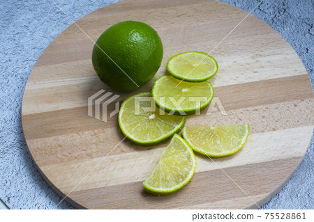 Juicy ripe citrus on an old wooden table - lime green whole and in round slices 75528861