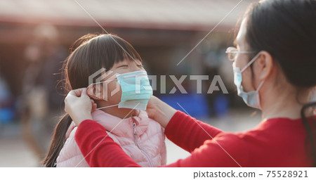 Mom helps girl wear mask 75528921