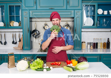 Go green. Handsome cook in kitchen. Chef following  75528930