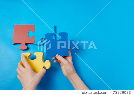 Top view hands of a autistic child arranging color puzzle symbol of awareness for autism spectrum disorder. Autism Awareness Day or month. 75529088