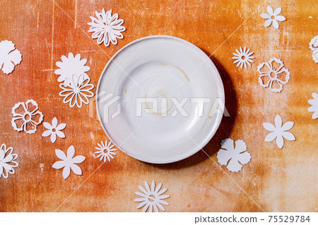 Empty white plate with paper flowers around 75529784