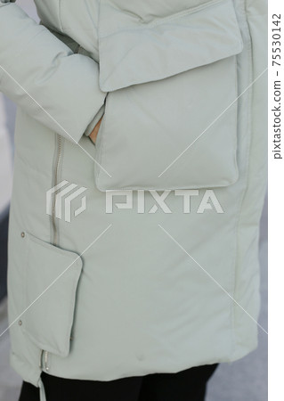 close up photo of white down coat with pocket detail and model hands close up photo close up photo of white down coat with pocket detail and model hands close up photo 75530142