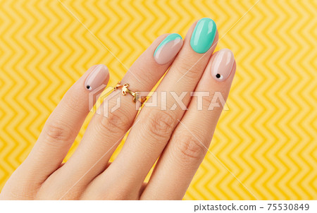 Womans hand with trendy turquoise manicure on yellow background 75530849