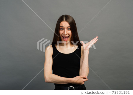 Cheerful young beautiful girl smiling winking showing tongue looking at camera over grey background. Cheerful young beautiful girl smiling winking showing tongue looking at camera over grey background. 75531191