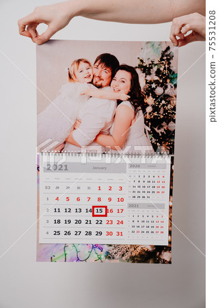 A woman holds it in his hands a calendar with a family photo. A woman holds it in his hands a calendar with a family photo. 75531208