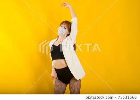 Female strip dancer in yellow studio in protective mask from covid 75531566