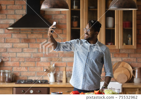 Joyful young black male cooking food and posing for selfie 75532962
