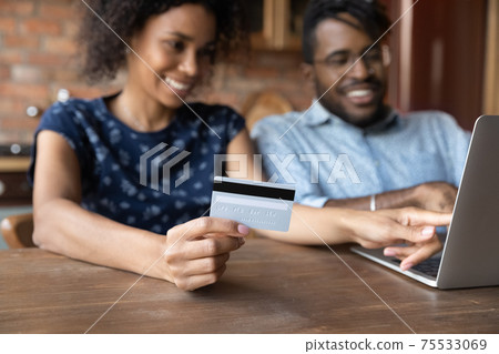 Millennial afro american spouses sit by laptop make cashless payment Millennial afro american spouses sit by laptop make cashless payment 75533069