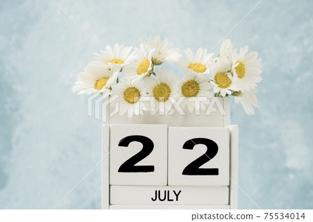 White cube calendar for july decorated with daisy flowers on blue 75534014