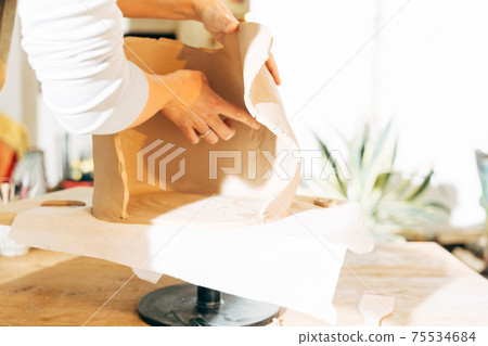 Closeup unknown woman preparing to work with wet clay in workshop 75534684