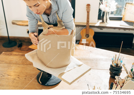 Master putting freshmade clay jar on wooden board in workshop Master putting freshmade clay jar on wooden board in workshop 75534695