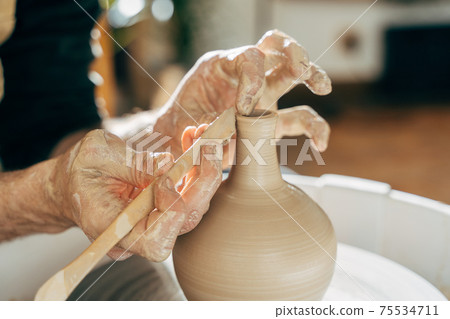 Concentrated master at the potter's wheel closeup Concentrated master at the potter's wheel closeup 75534711