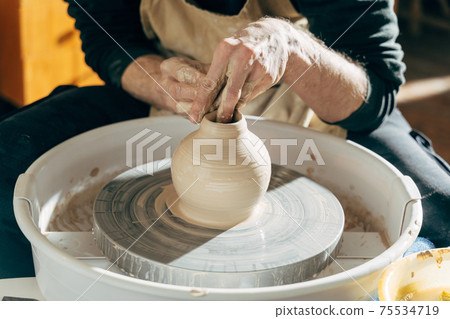 Male brunette sculpt a utensils near wooden table with tools 75534719