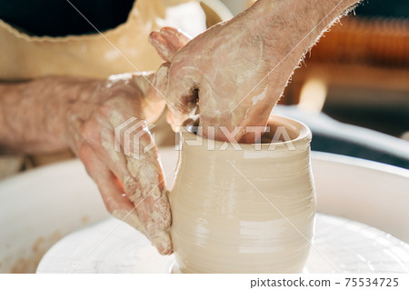 Caucasian man making vessel daytime of white clay in fast moving circle 75534725