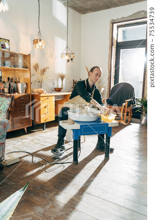 Man working with potter wheel and raw fireclay Man working with potter wheel and raw fireclay 75534739