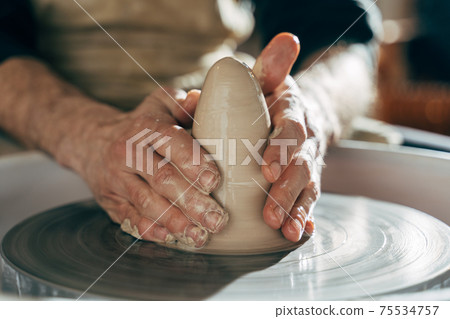 Potter makes pot of clay on potter's wheel Potter makes pot of clay on potter's wheel 75534757