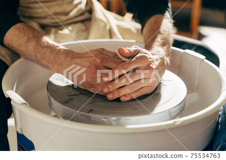 Sculptor in the workshop makes a jug out of earthenware Sculptor in the workshop makes a jug out of earthenware 75534763