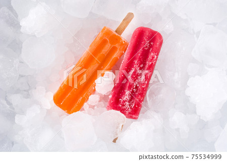 Orange and strawberry popsicles on ice cubes. Top view Orange and strawberry popsicles on ice cubes. Top view 75534999