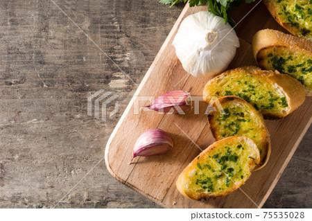 Garlic bread slice on wooden table.  75535028