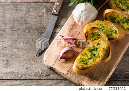 Garlic bread slice on wooden table.  75535032