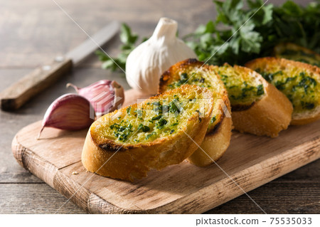 Garlic bread slice on wooden table.  75535033