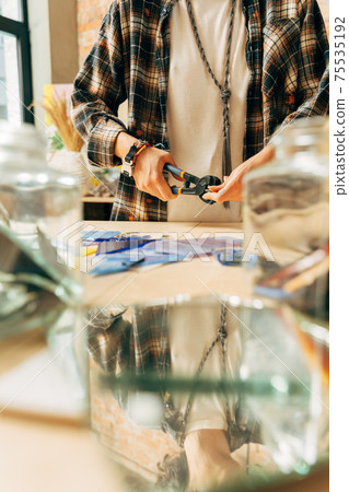Artist holding mosaic tools and hand crafting, while using tweezers to make mosaic 75535192