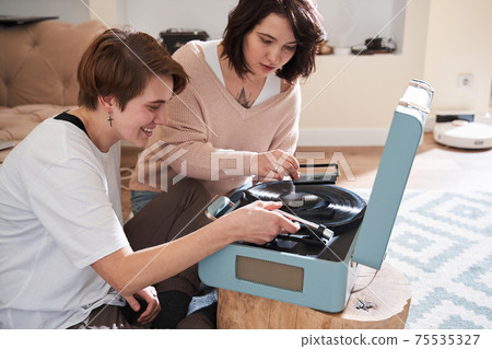 Lesbians sitting near player and turning it on while preparing to listening music Lesbians sitting near player and turning it on while preparing to listening music 75535327
